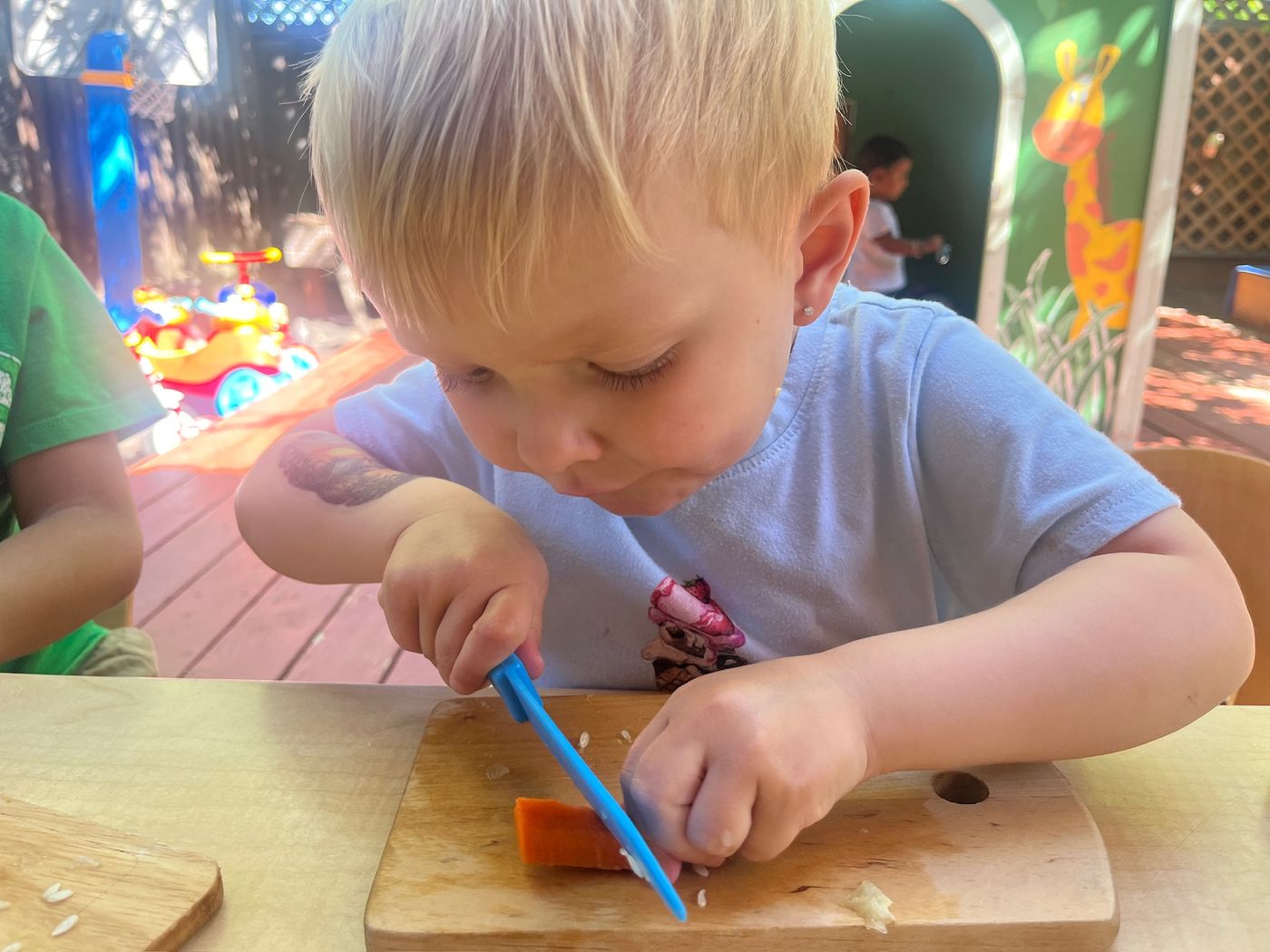 Older child practicing knife skills cutting a carrot