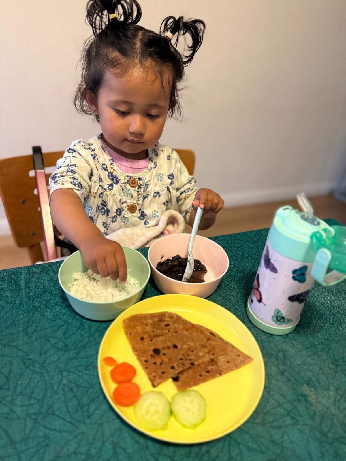 Toddler enjoying a home-cooked meal of roti, rice, and dal